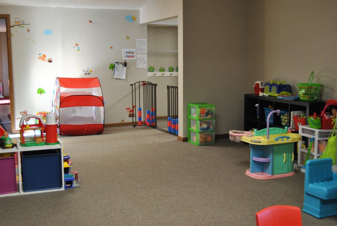 Playroom with various toys, including a red and white tunnel and play kitchen