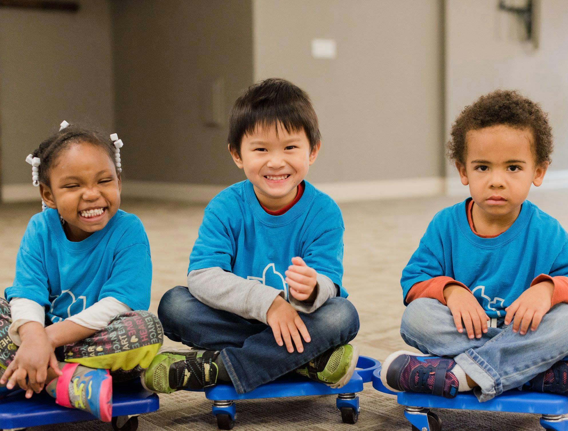 Three children sitting on scooter boards