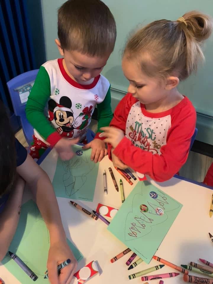 Two children drawing at a table with crayons
