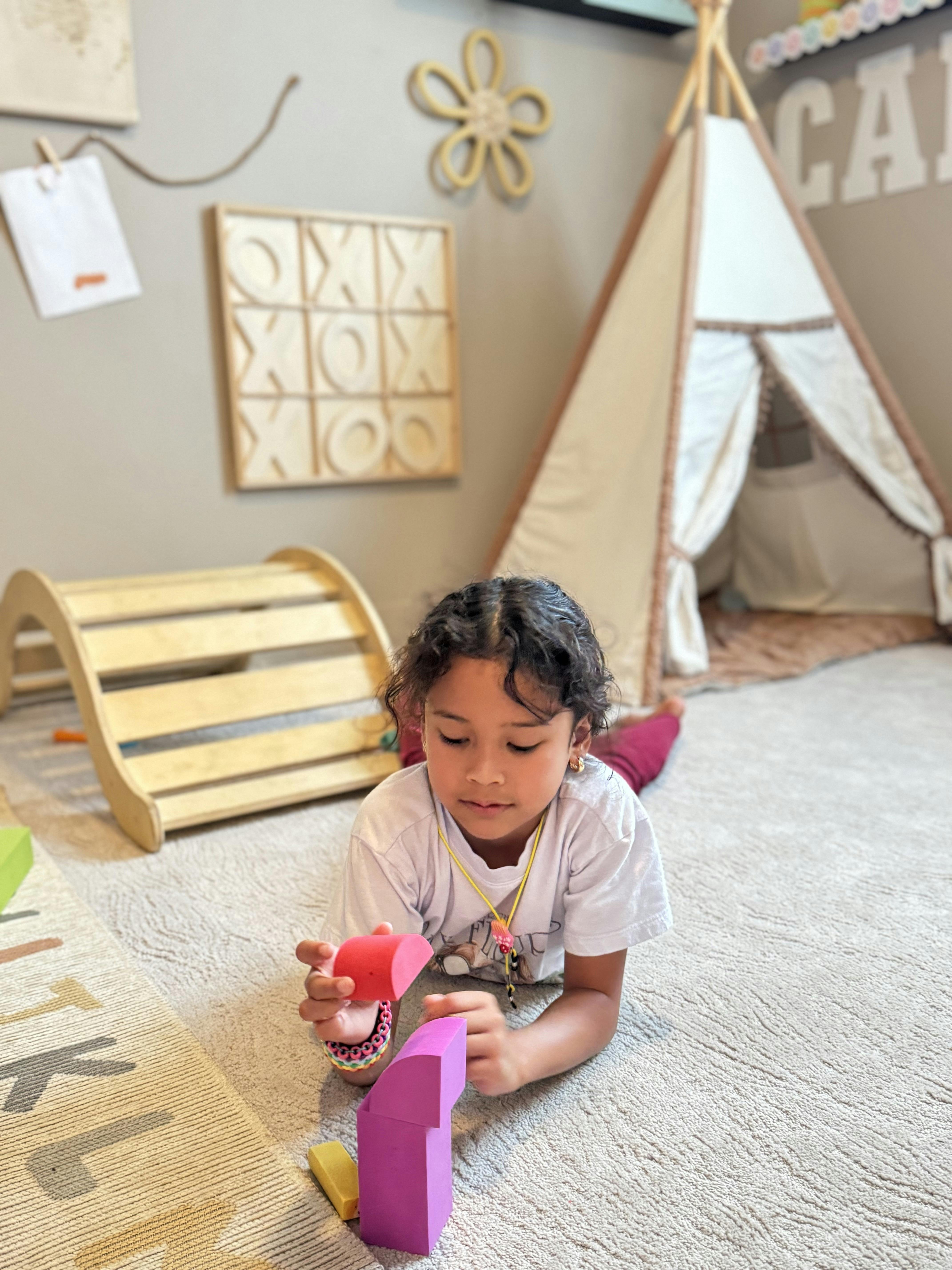 Child lying on a carpet playing with colorful building blocks
