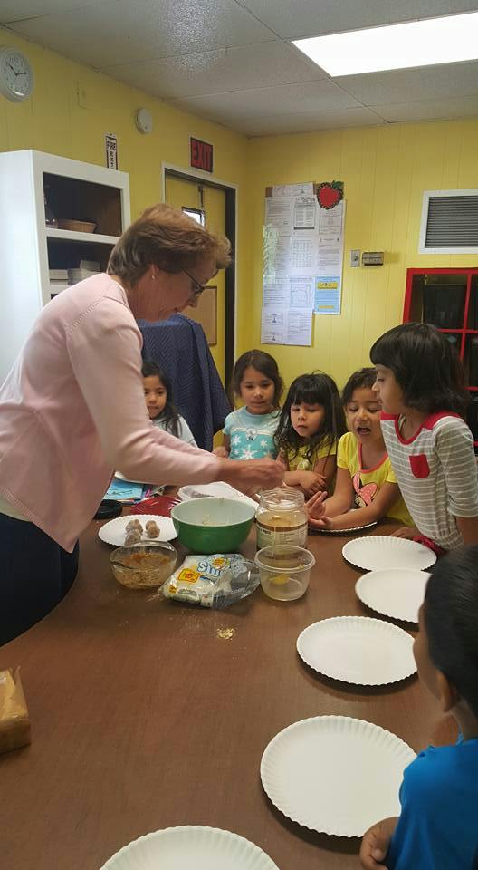 Person helping children at a table with bowls and plates