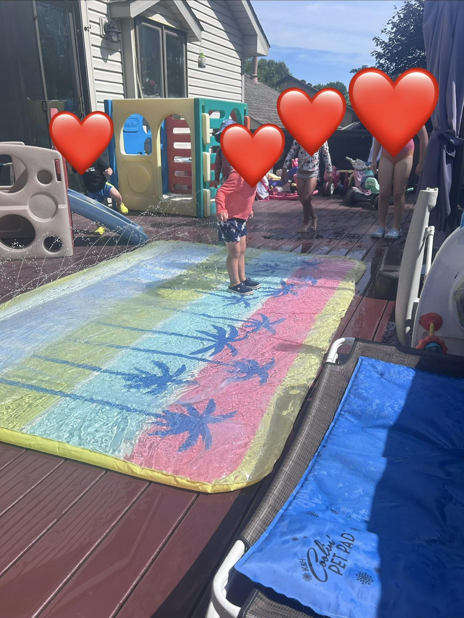 Children playing on a water mat on a deck