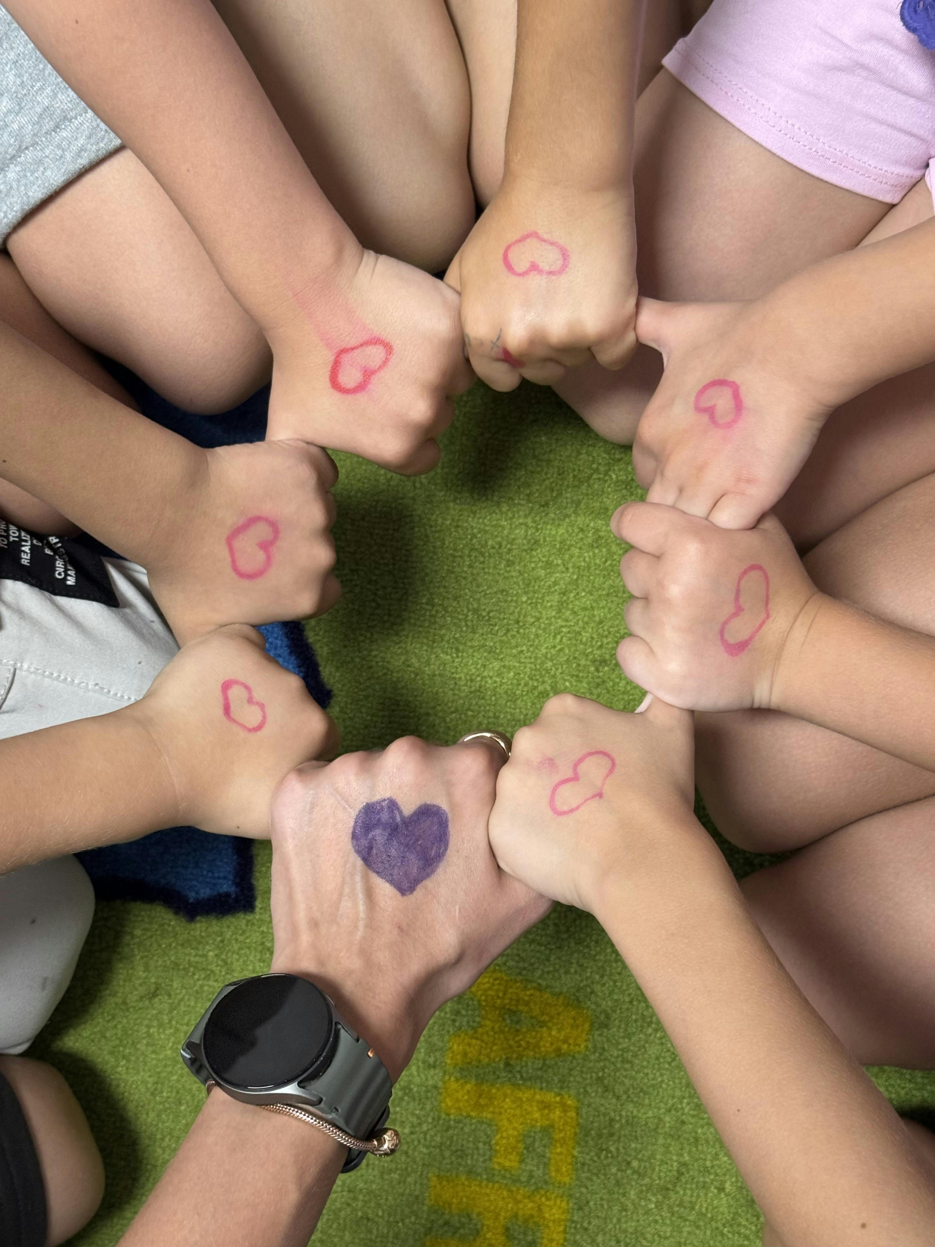 People forming a circle with their fists marked with hearts
