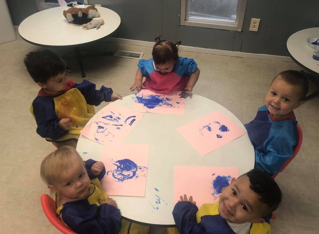 Children finger painting at a table