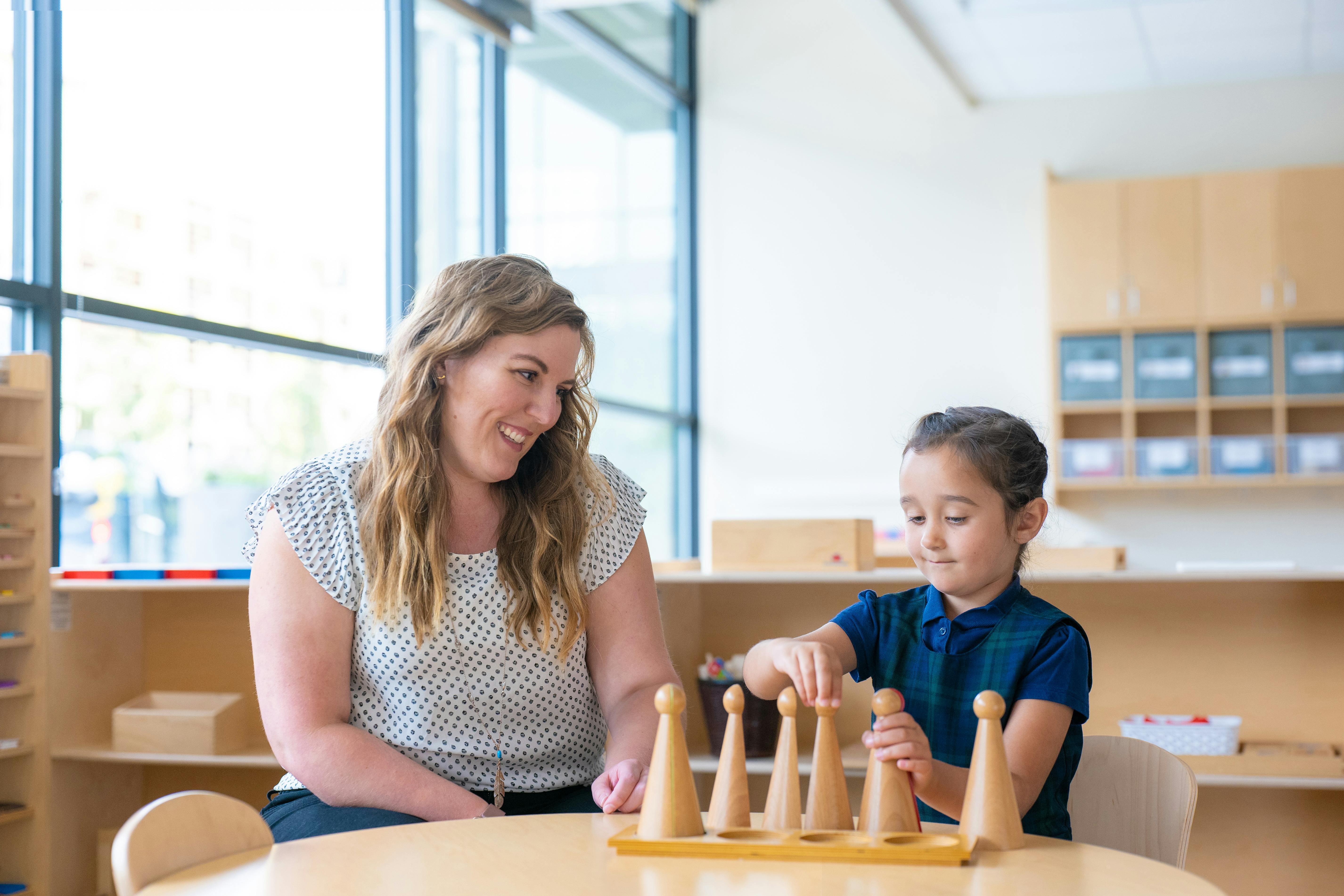 Person and child playing with wooden cones in a classroom