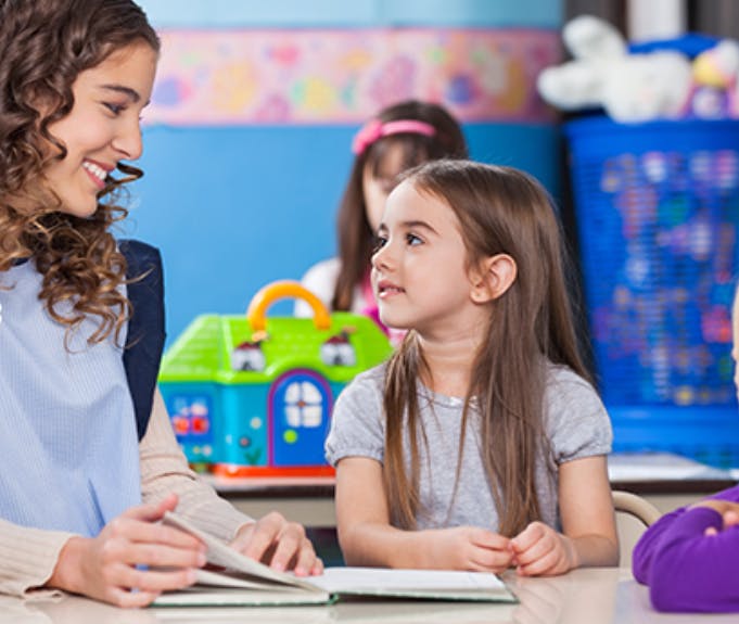Person reading a book to a child in a classroom