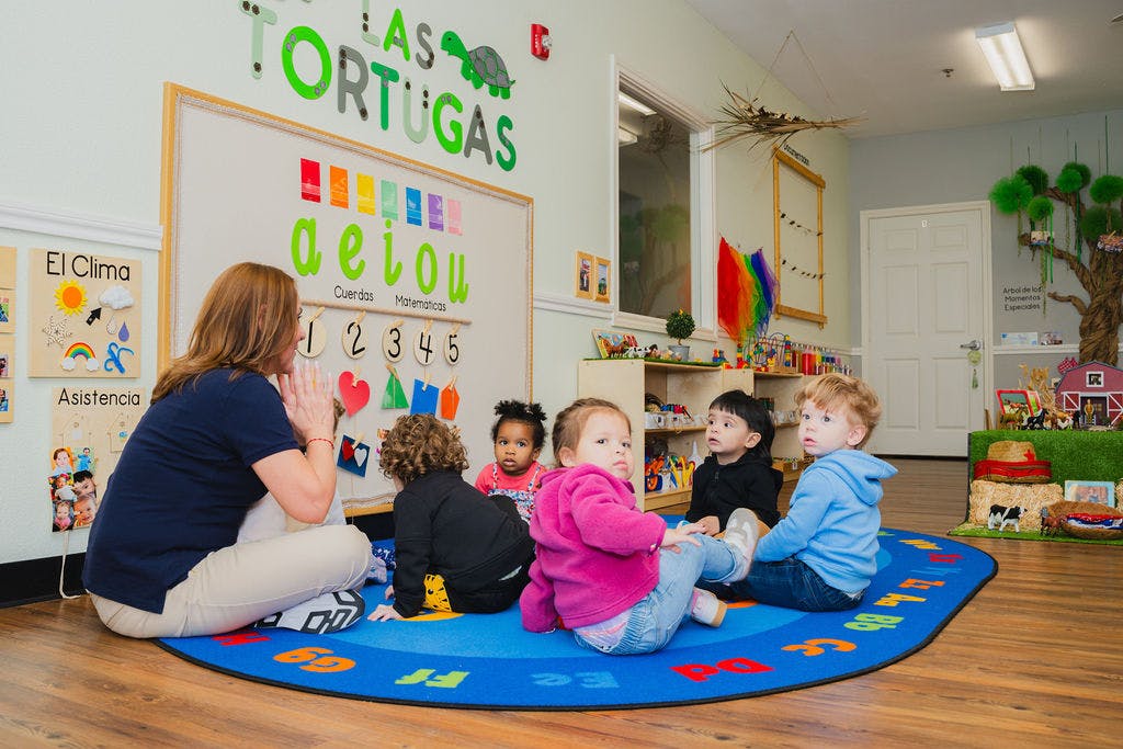 Adult and children sitting on a rug in a classroom
