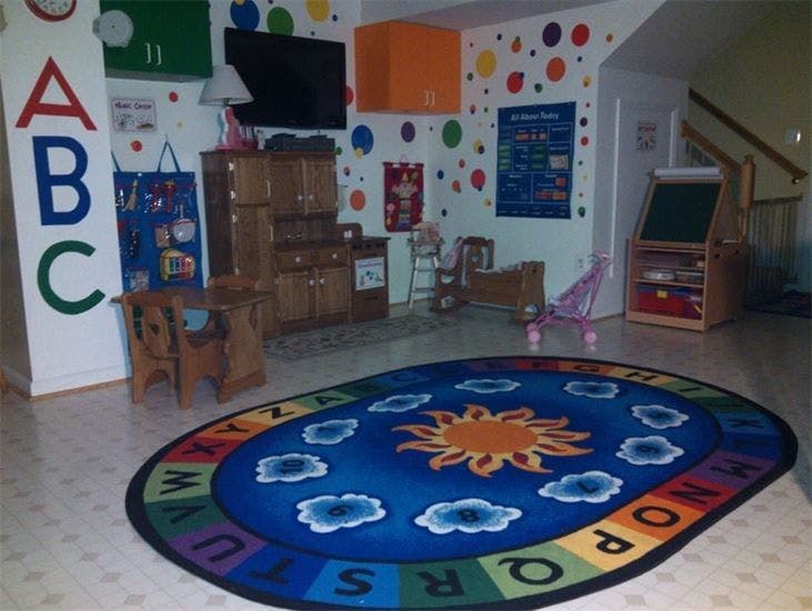 Playroom with an alphabet rug, small wooden furniture, and wall decorations