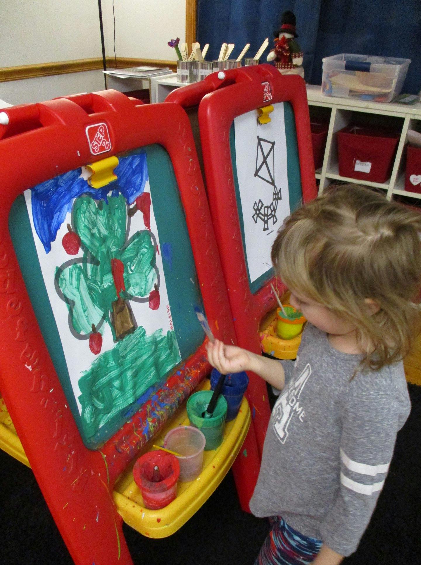 Child painting a tree on an easel