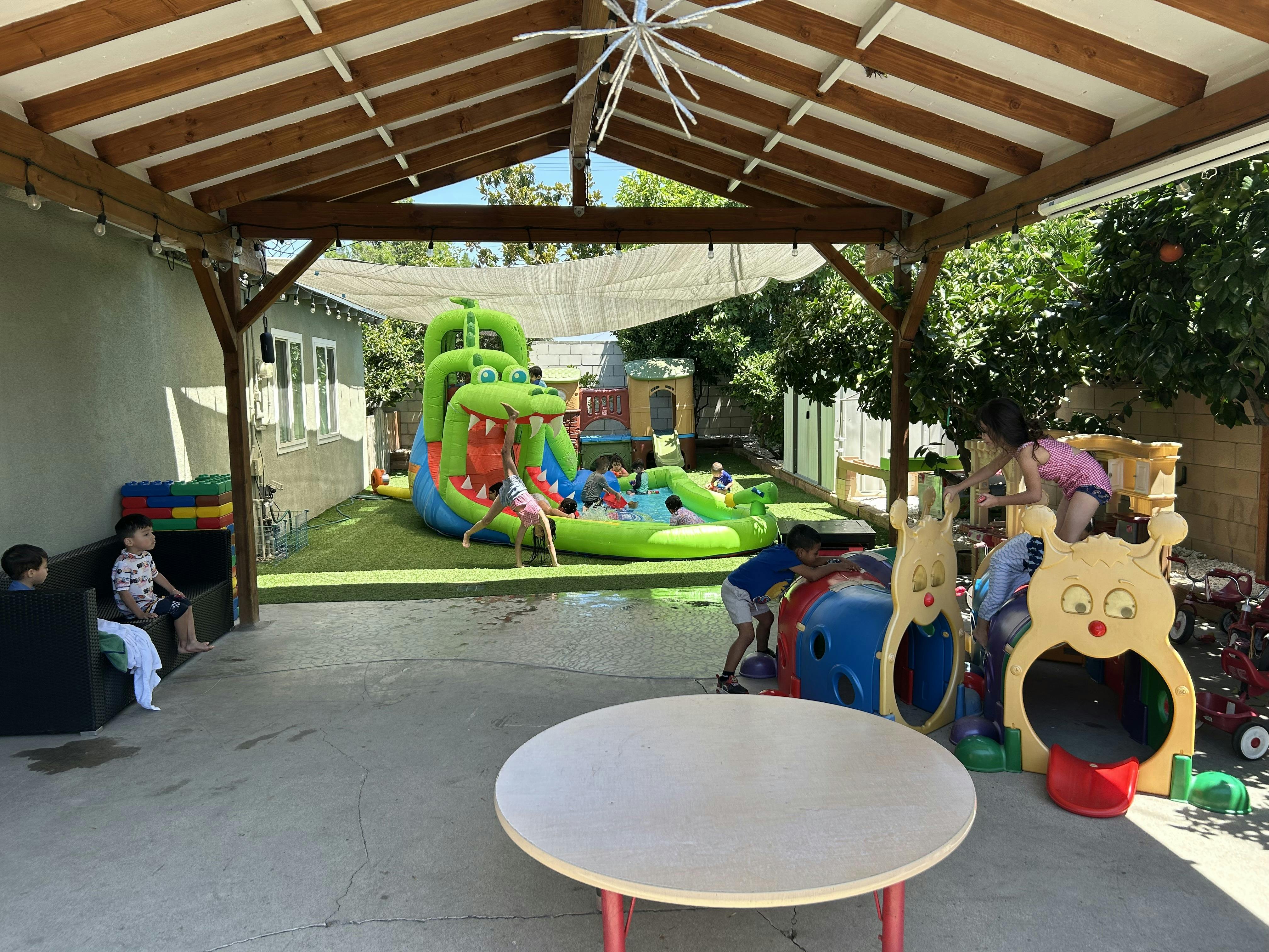 Children playing in a backyard with a large inflatable slide and play structures