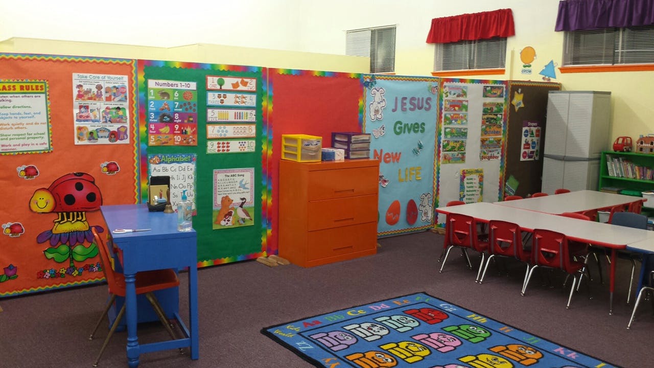 Classroom with colorful bulletin boards, small tables, and a rug