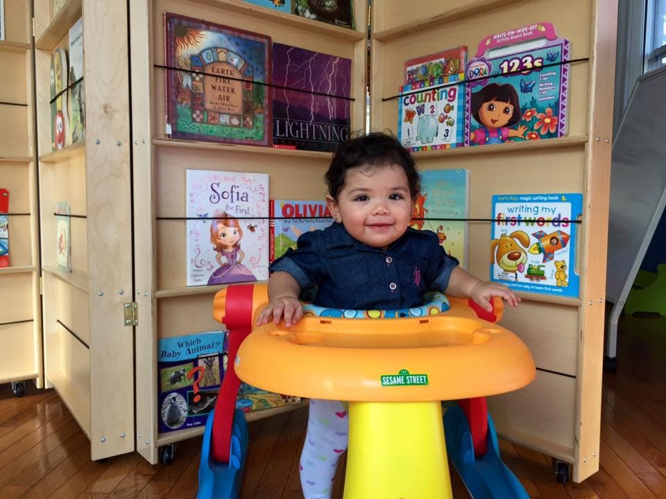 Child in a baby walker in front of bookshelves