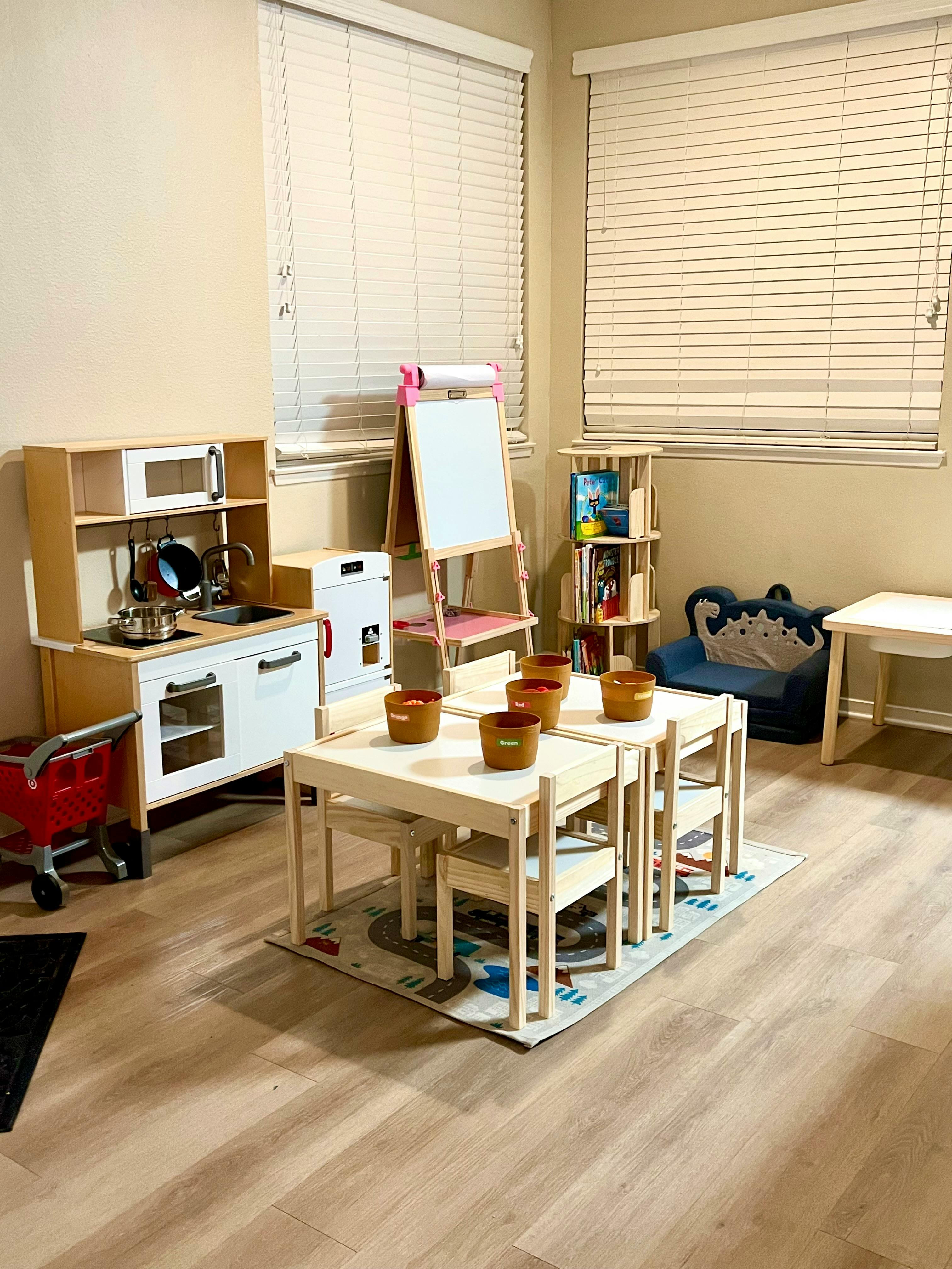 Children's play kitchen, table and chairs, and easel in a room