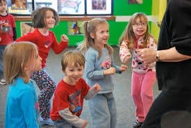 Children dancing with an adult in a classroom