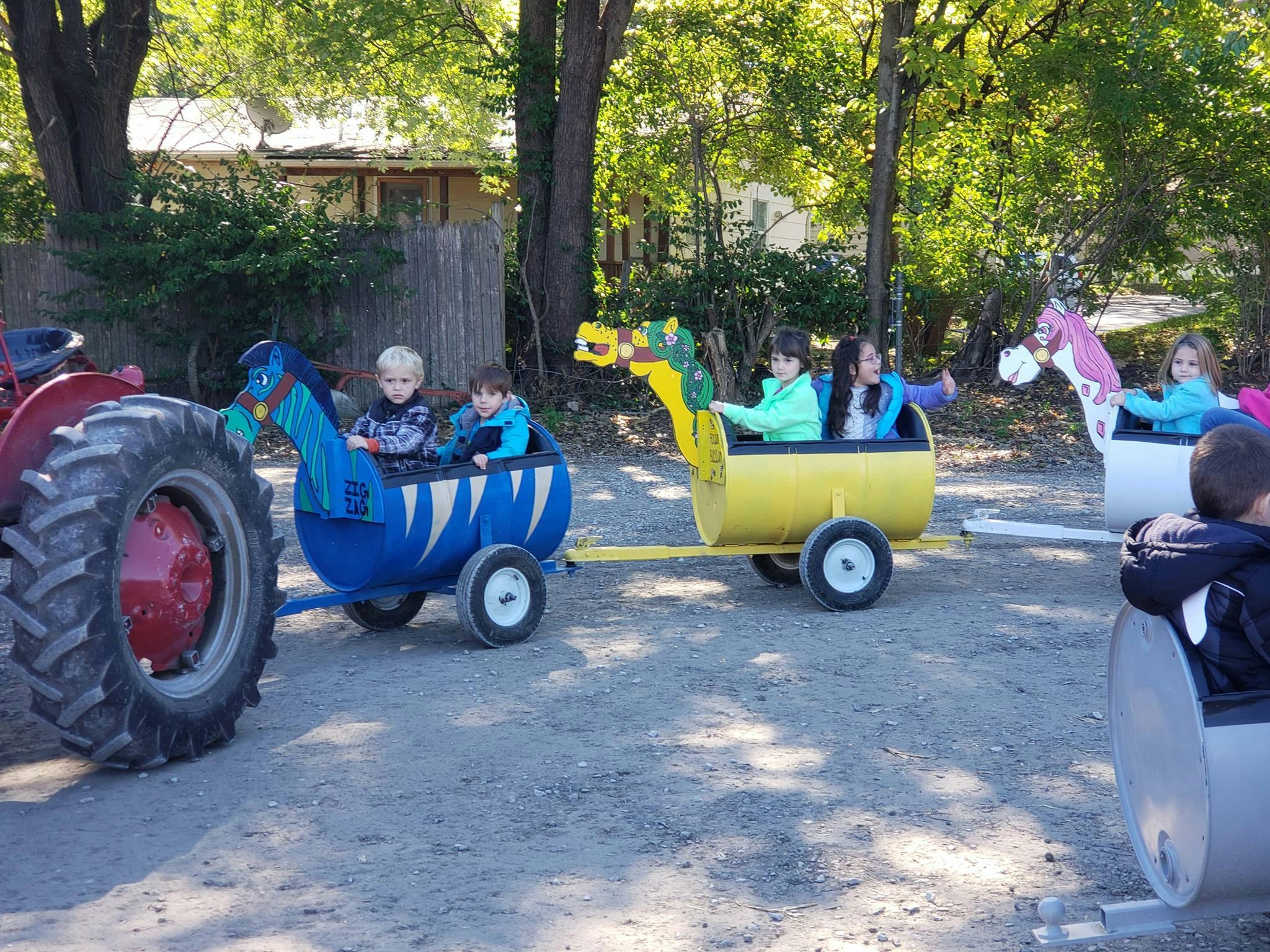 Children riding in barrel train cars pulled by a tractor