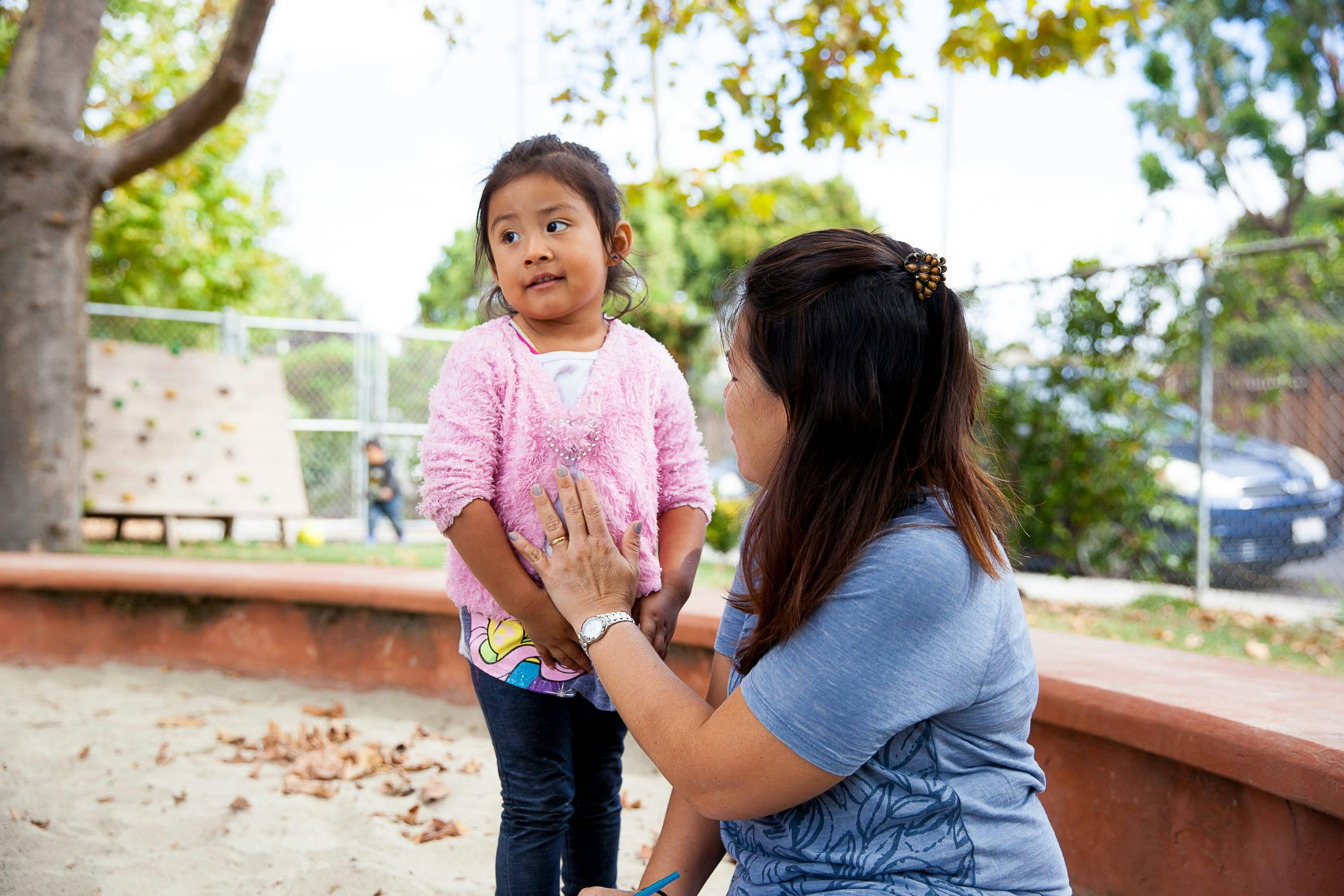 Adult kneeling and talking to a child