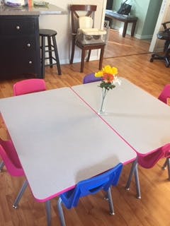 Two small tables with chairs and a vase of flowers