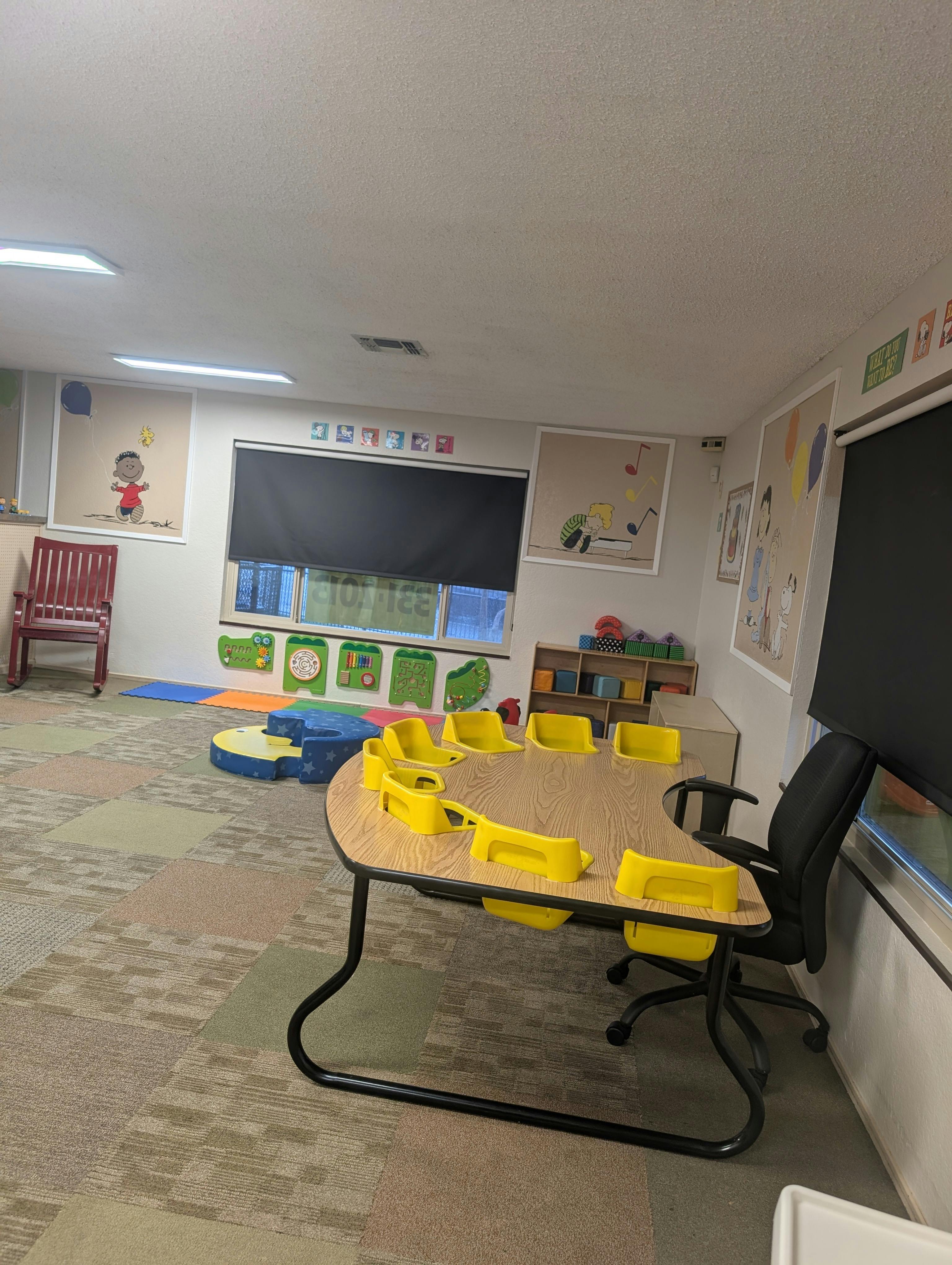 Classroom with a table surrounded by yellow children's chairs