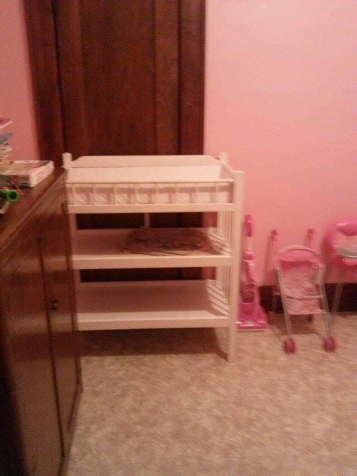 White changing table with shelves next to a wooden cabinet