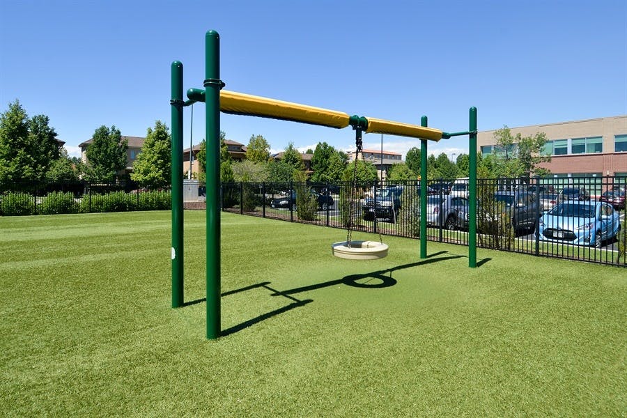 Playground with green poles and yellow bar over artificial turf