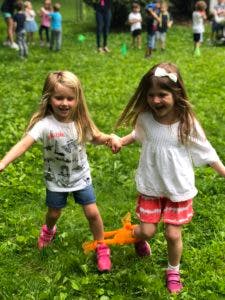 Two children holding hands and running in grass