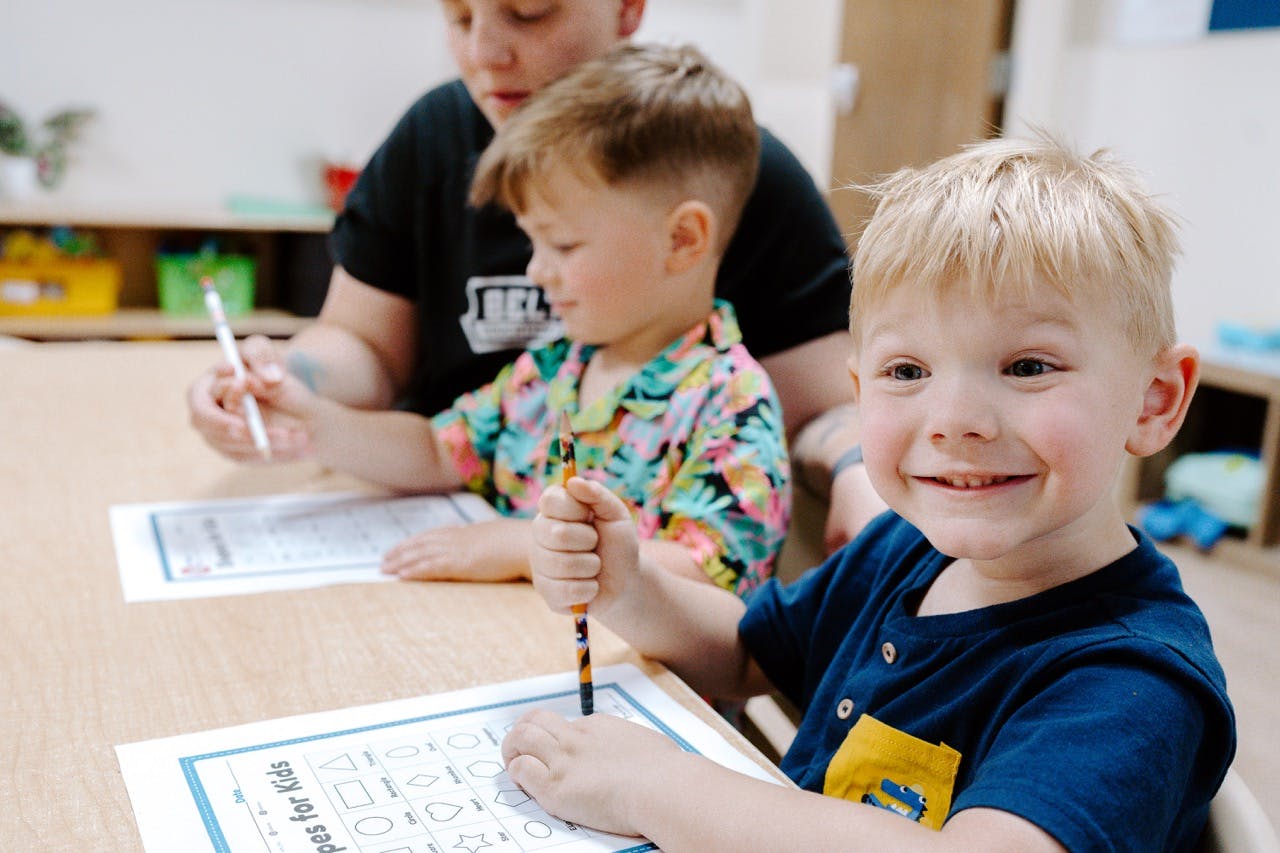 Three children at a table with papers and pencils