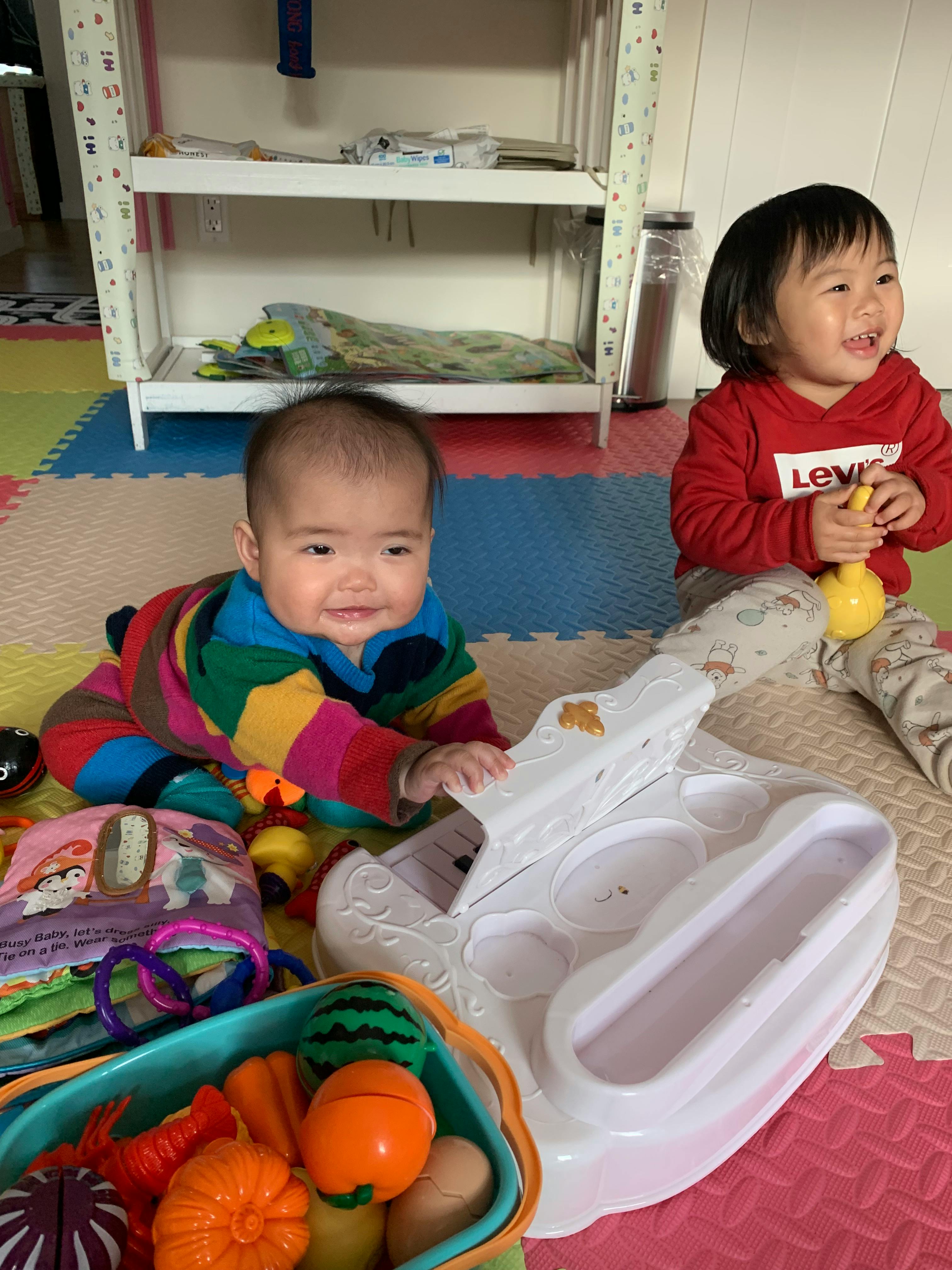 Two children playing on a mat with toys