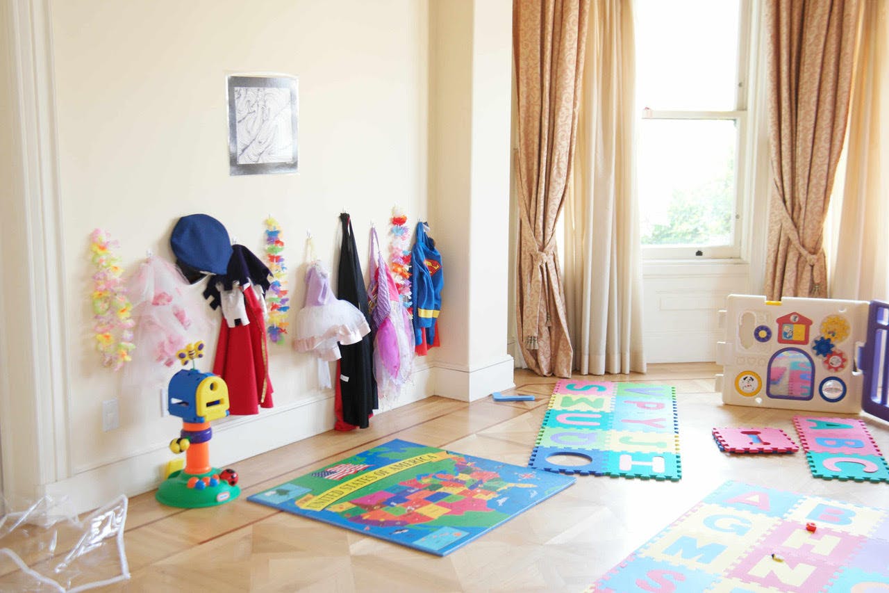 Playroom with dress-up clothes on hooks and colorful play mats on the floor