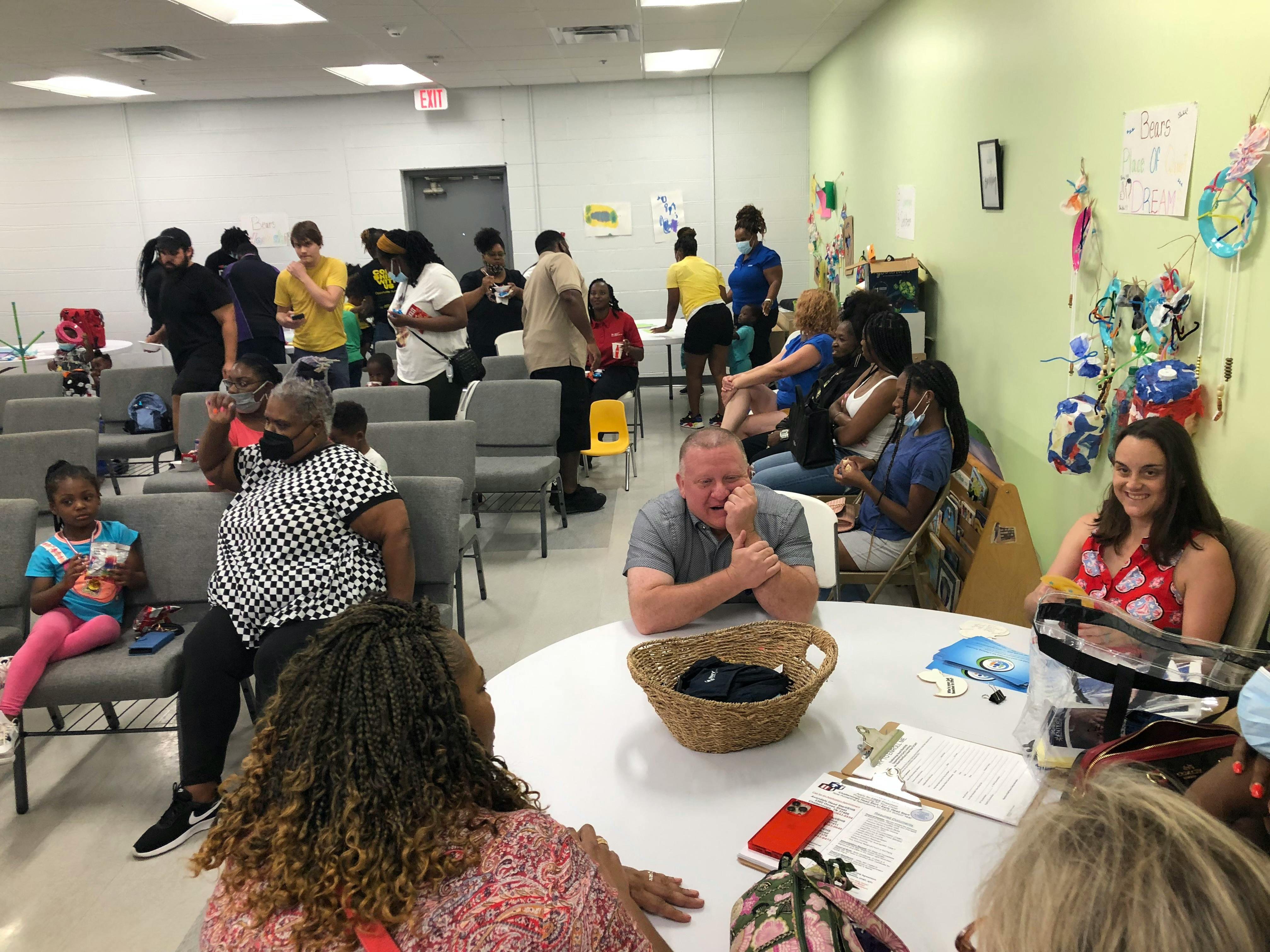 People gathered in a room with some sitting at tables and others in rows of chairs