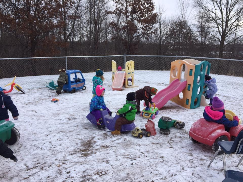 Children playing on playground equipment in snow