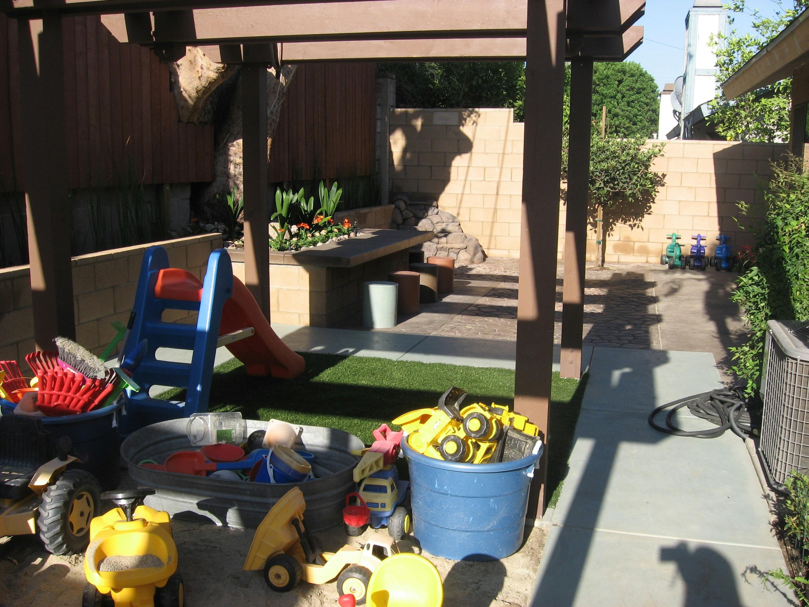 Childrens play area with plastic toys slide and buckets on artificial turf