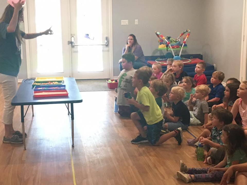 Person presenting to a group of children sitting on the floor