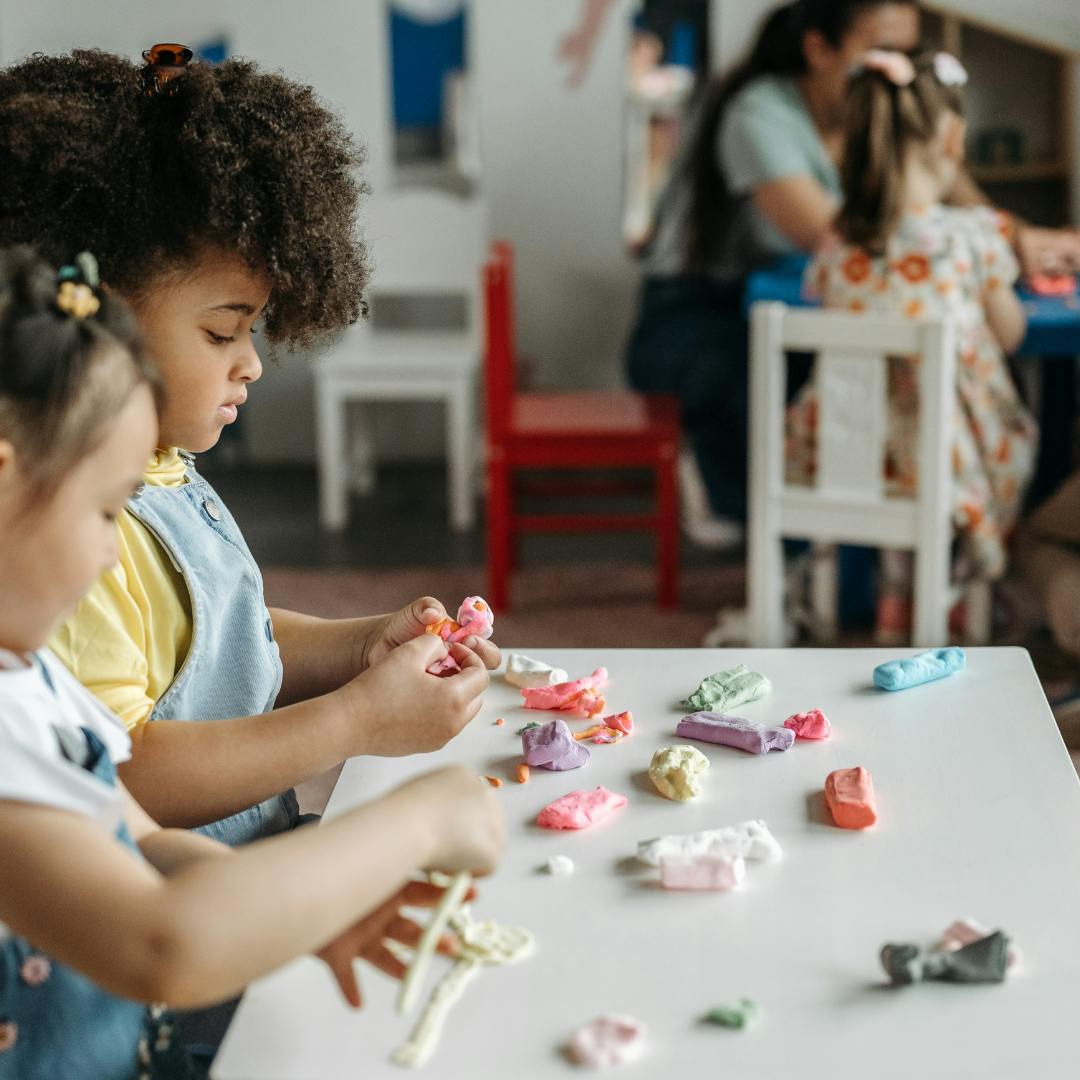 Two children playing with colorful clay at a table