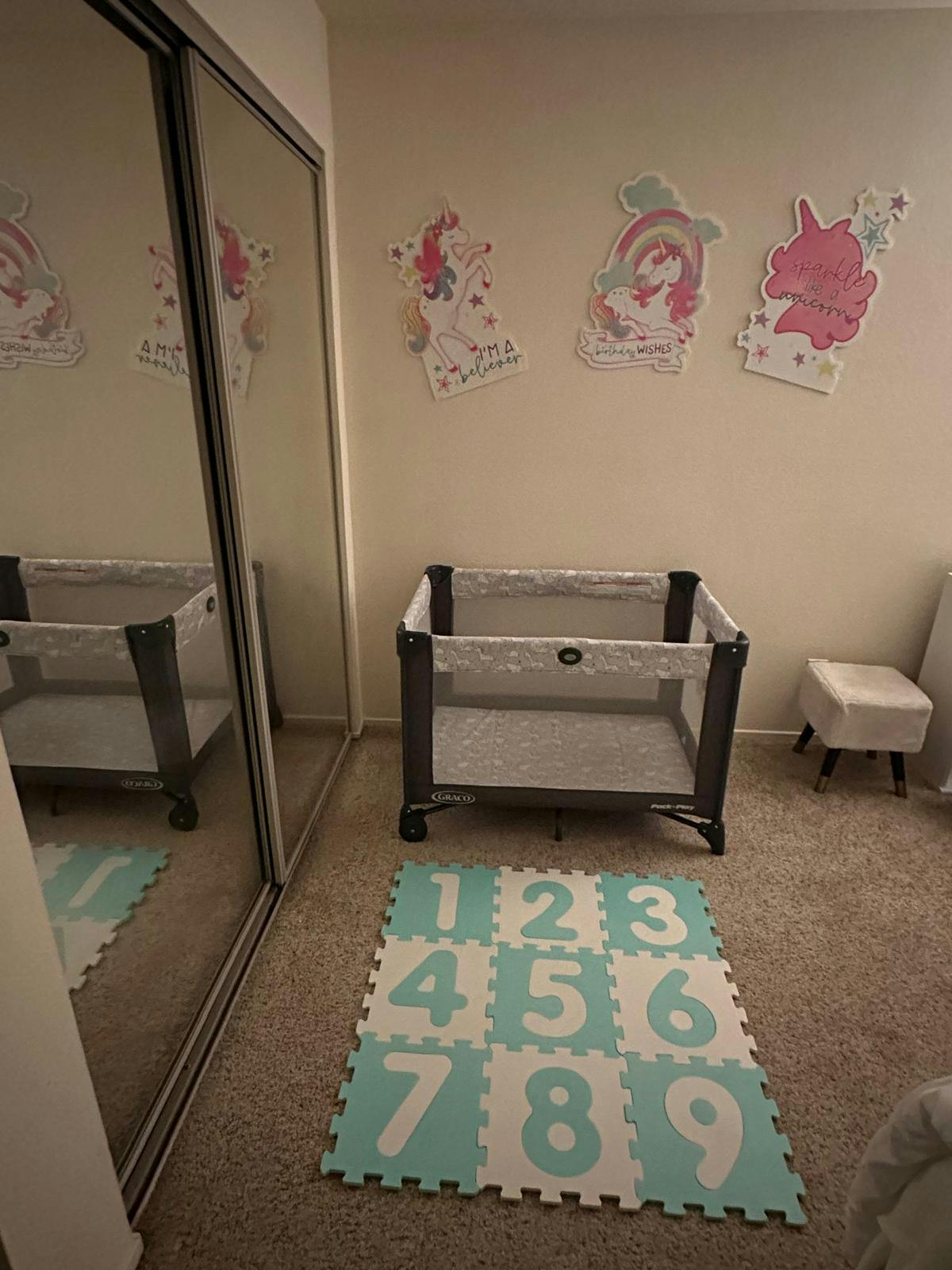 Playpen with a number mat on the floor and unicorn wall decals