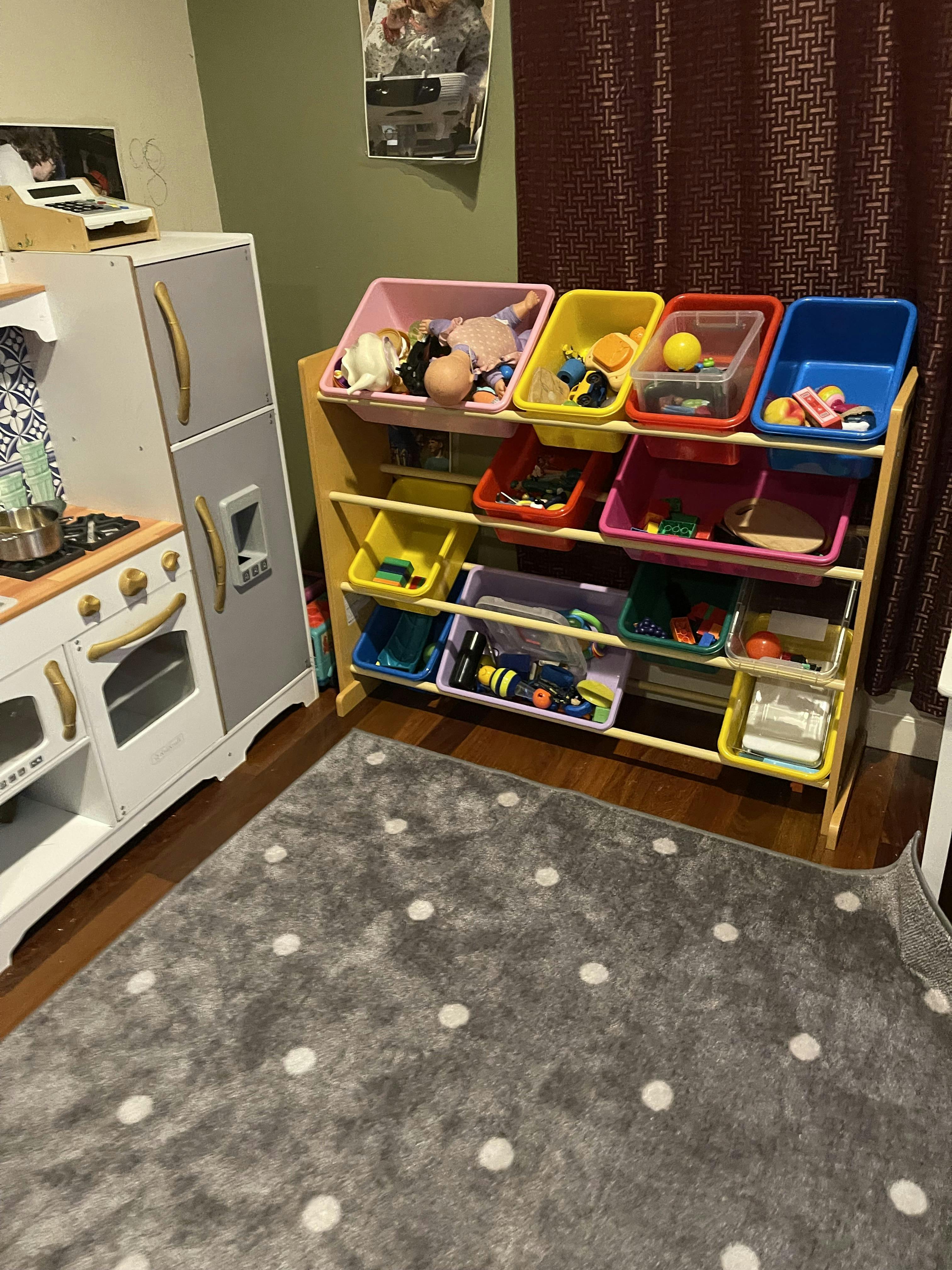 Toy organizer with colorful bins filled with toys and a play kitchen