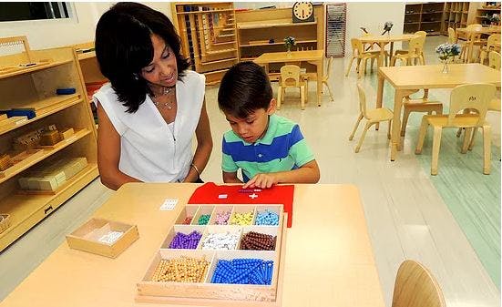 Person and child at a table with a box of colorful beads