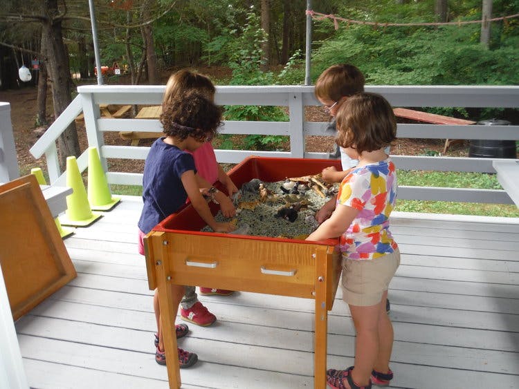Children playing in a sand table on a deck
