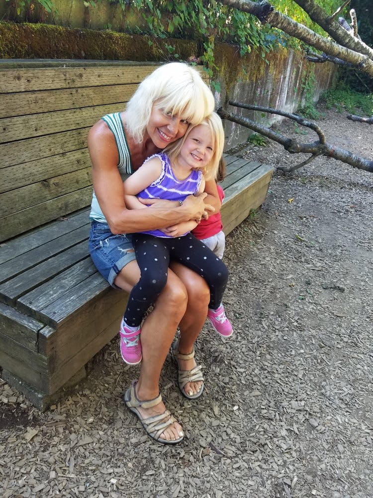 Person holding a child on their lap on a wooden bench