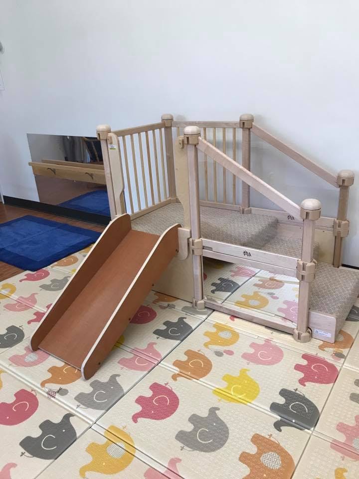 Indoor playground with a slide and stairs on an elephant-patterned mat
