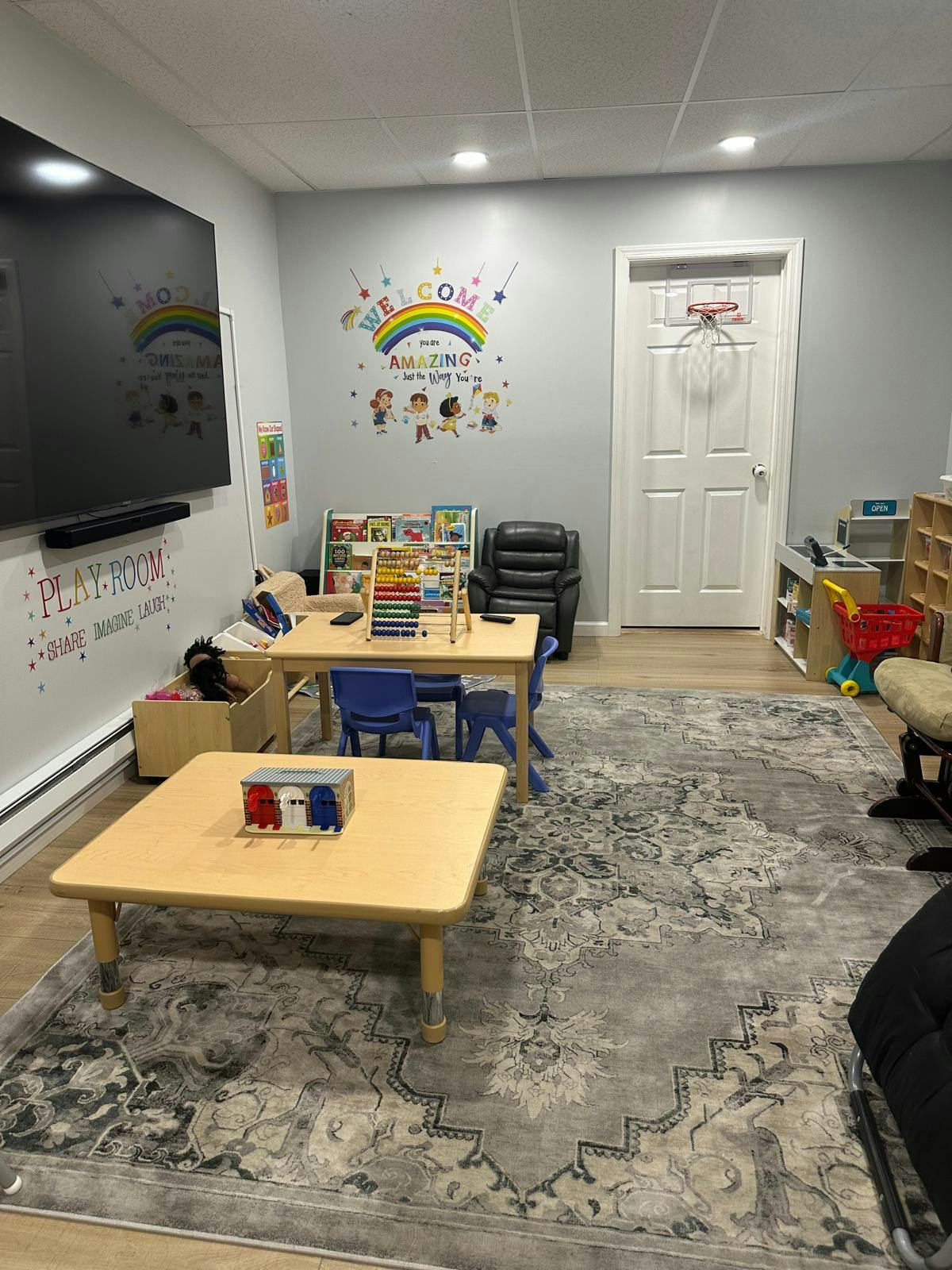 Playroom with small tables, chairs, and a large TV screen