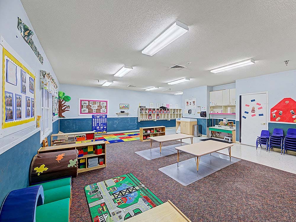 Empty colorful preschool classroom with small tables and chairs