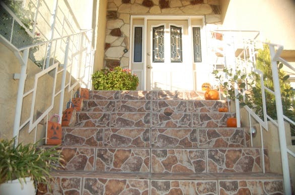 Tiled outdoor staircase leading to a white door with decorative glass panels