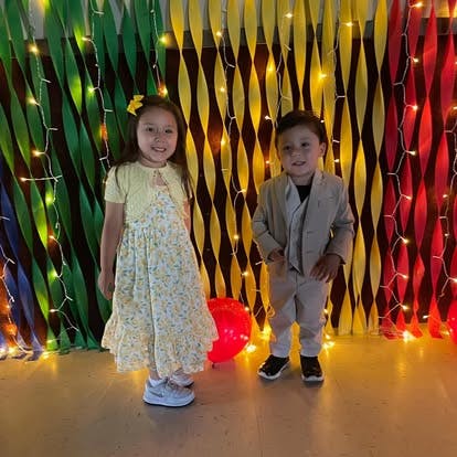 Two children standing in front of a colorful background with lights