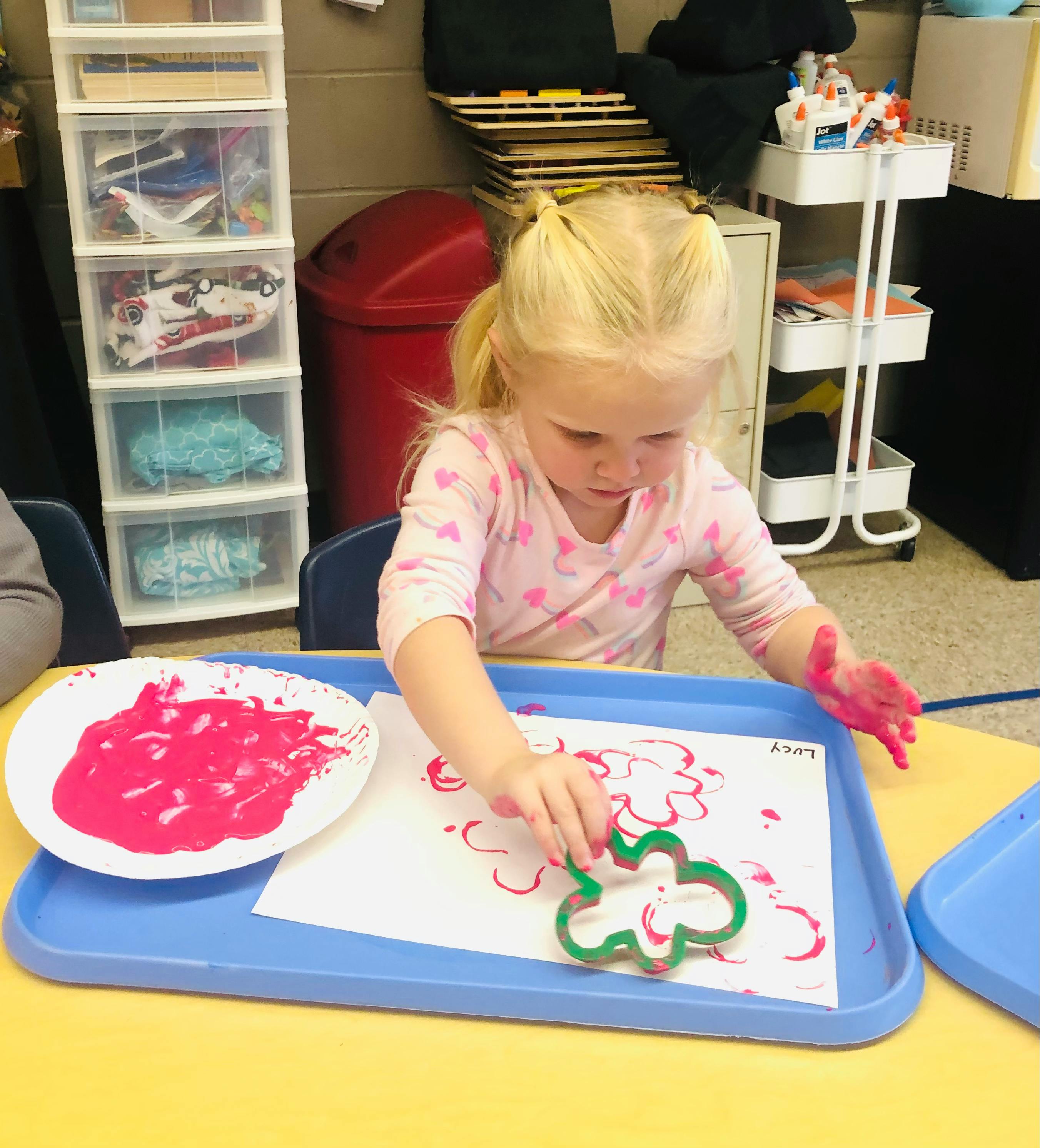 Child using a cookie cutter to stamp paint on paper