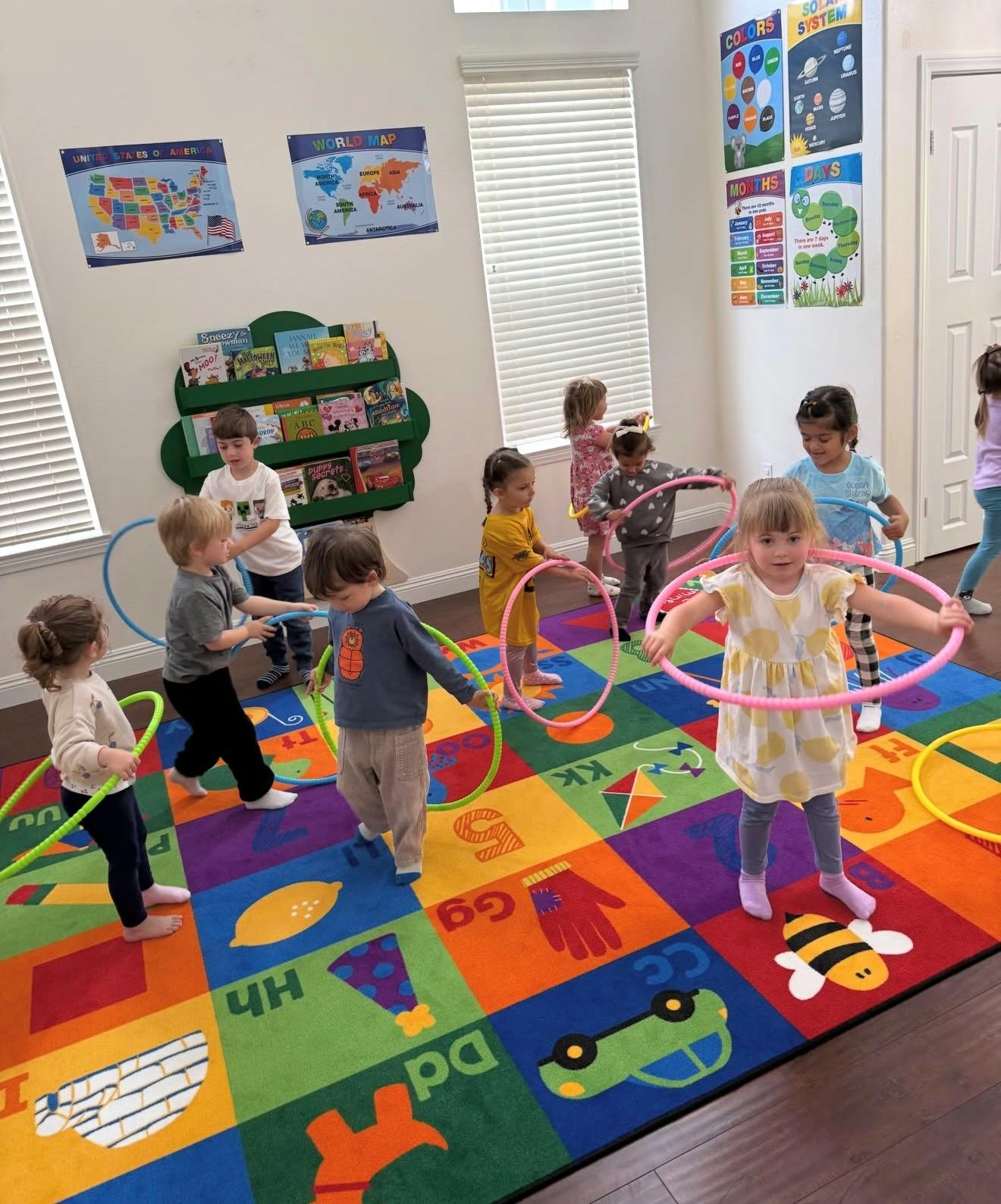 Children playing with hula hoops on a colorful educational floor mat