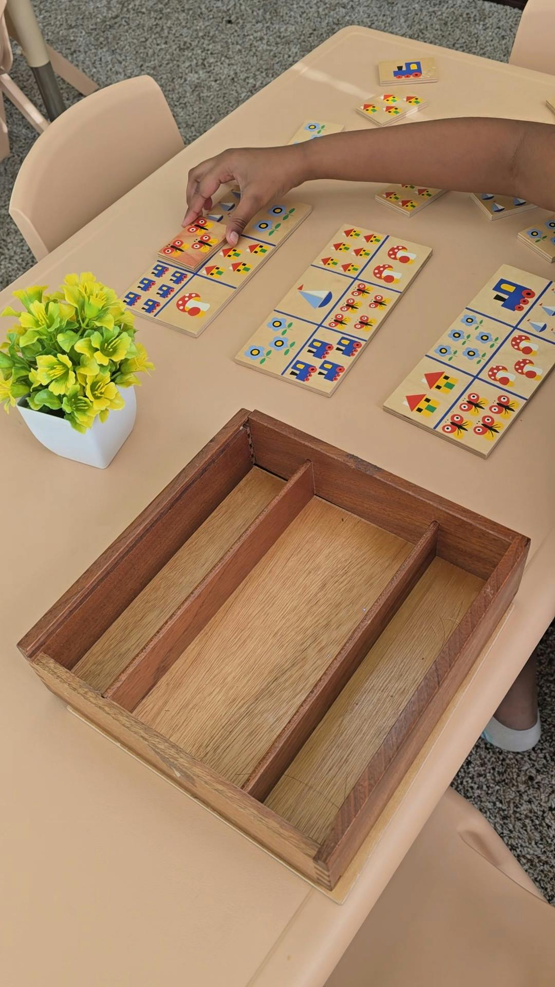 A person's hand placing a pattern block onto a board game