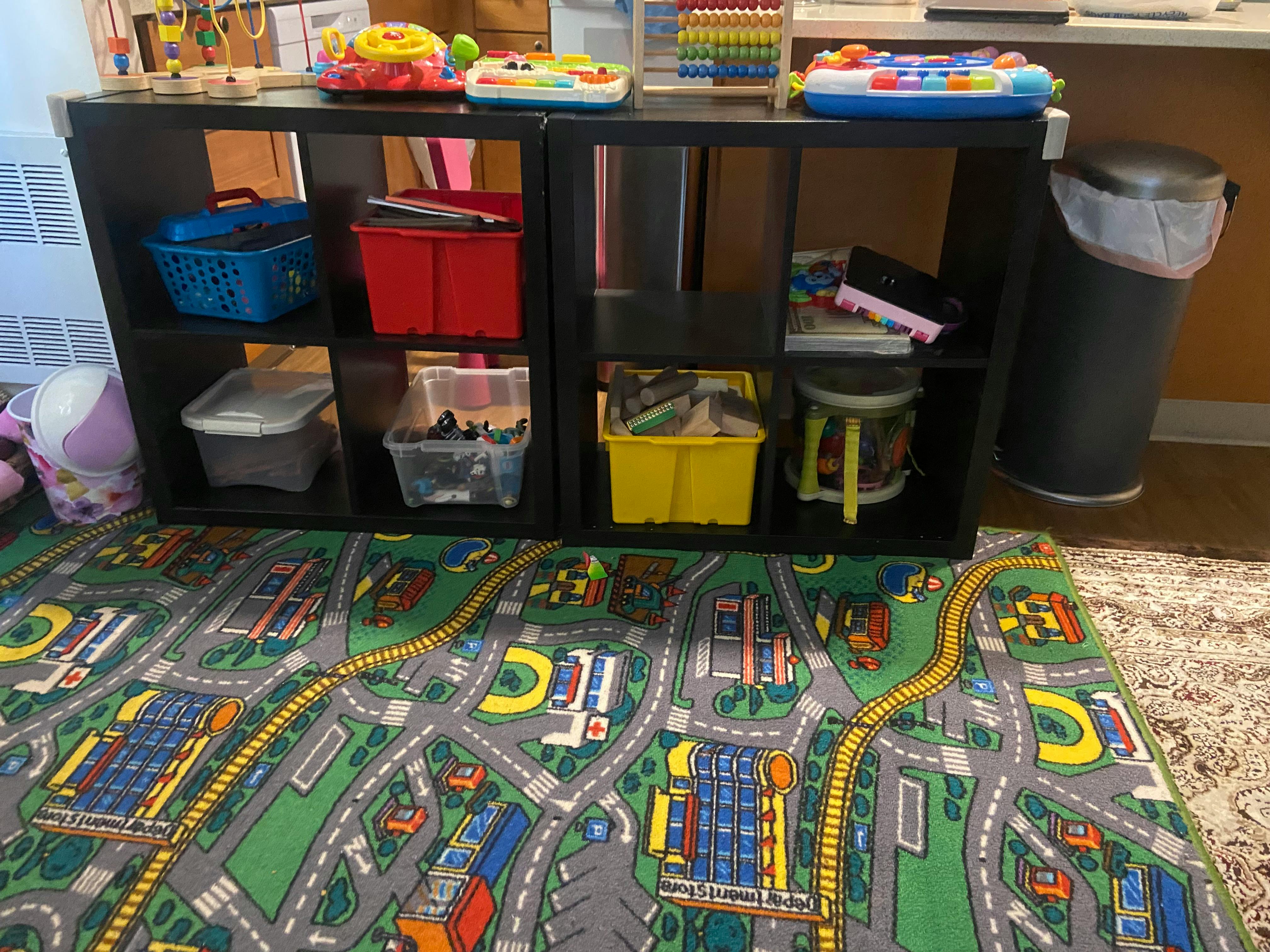 Playroom with toy storage shelves and a road map rug