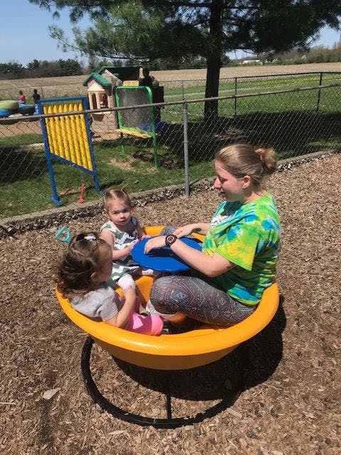 Person and two children sitting in a yellow spinning toy