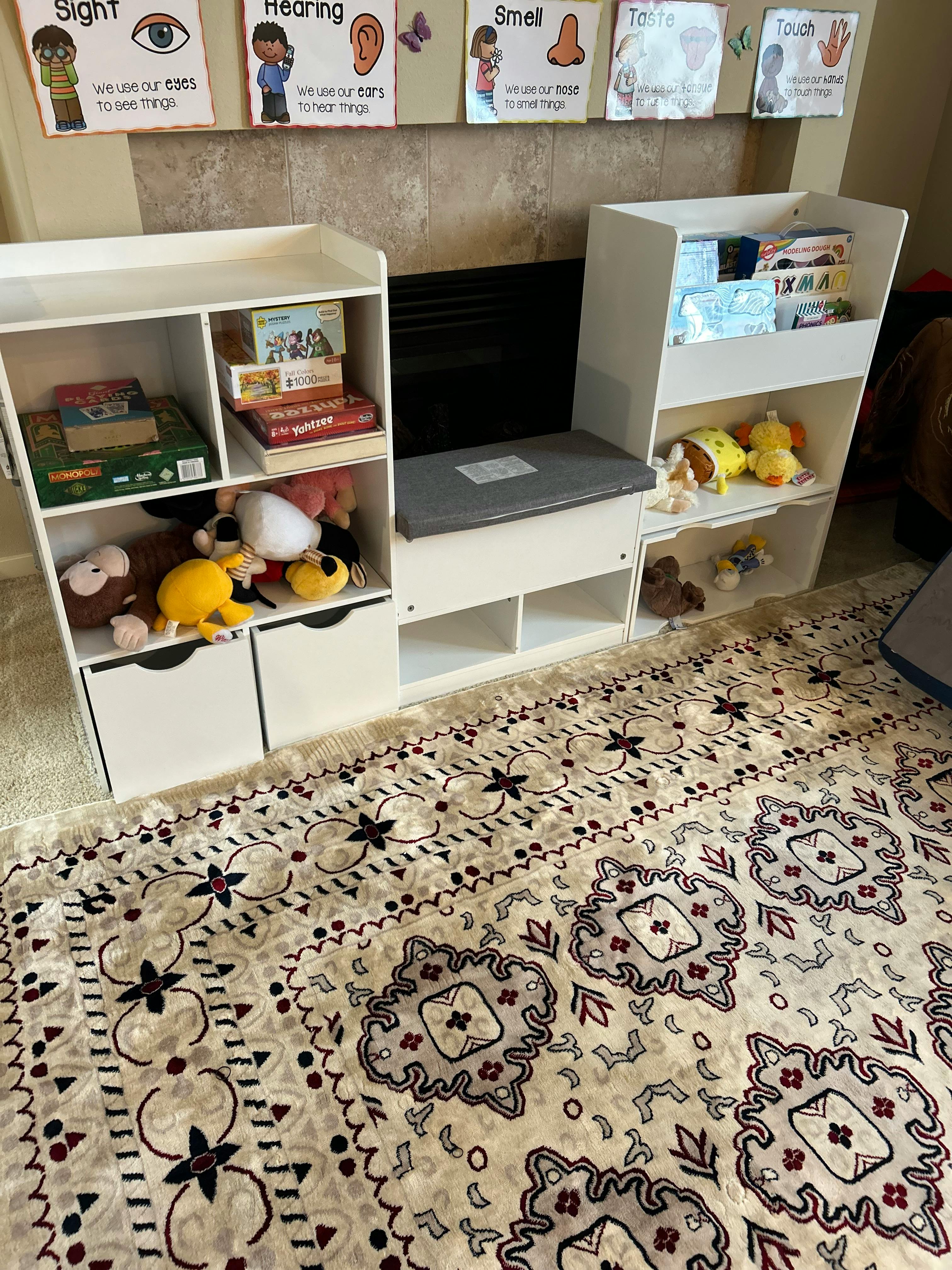 White storage shelf containing board games and plush toys with posters on wall