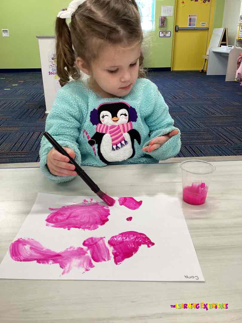 Child painting with pink paint on paper